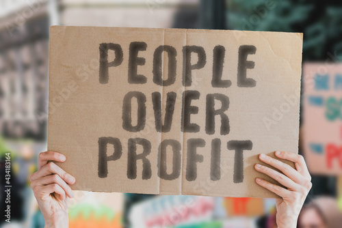 The phrase " People over profit " on a banner in hand with blurred background. Business. Money. Earnings. Revenue. Environment. Protection. Climate change. Globe