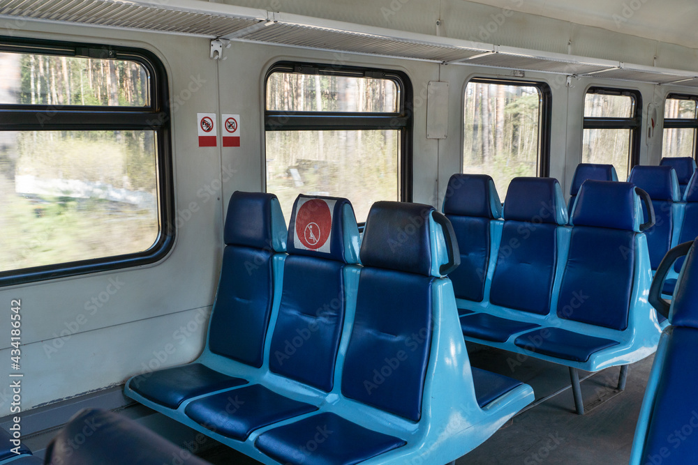 Empty wagon in train with blue chairs and red round stickers with restriction that forbid to take up middle seat in row to reduce number of passengers.. Traveling in new reality, covid restrictions