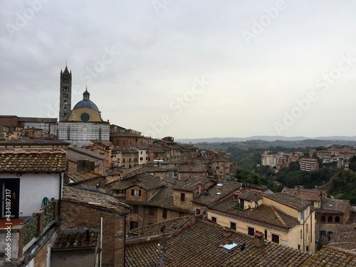 SIENA, ITALY. Panorama view of Siena medieval buildings. Evening, cloudy sky, Tuscany hills on a background, tile rooftop. Date of photo is 01.10.2015