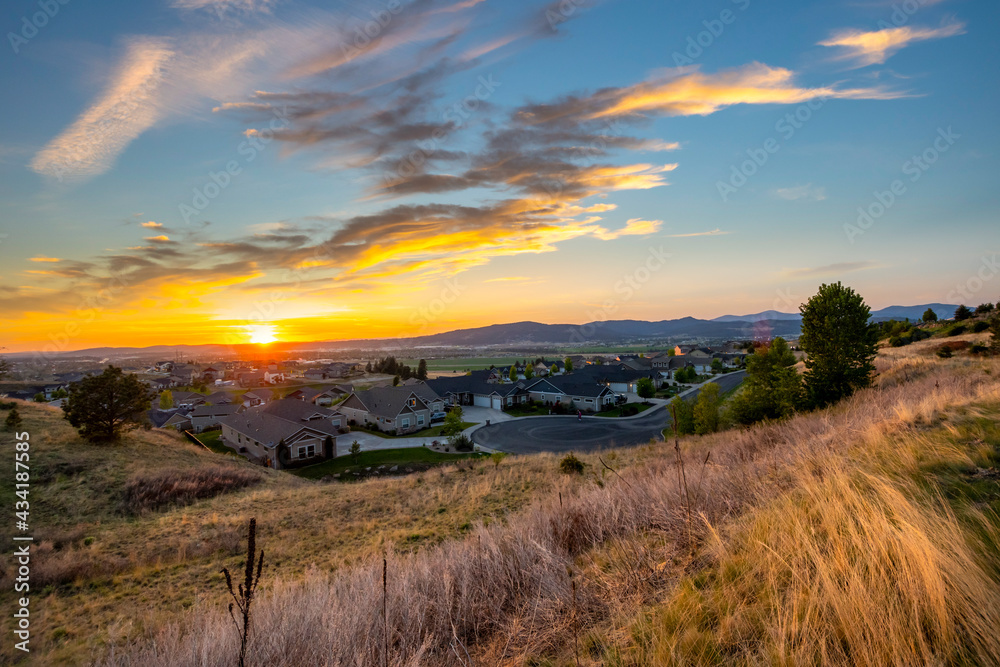 A setting sun during mid summer showing the cities of Spokane, Spokane Valley, and Liberty Lake Washington, USA, from a hilltop overlooking homes.