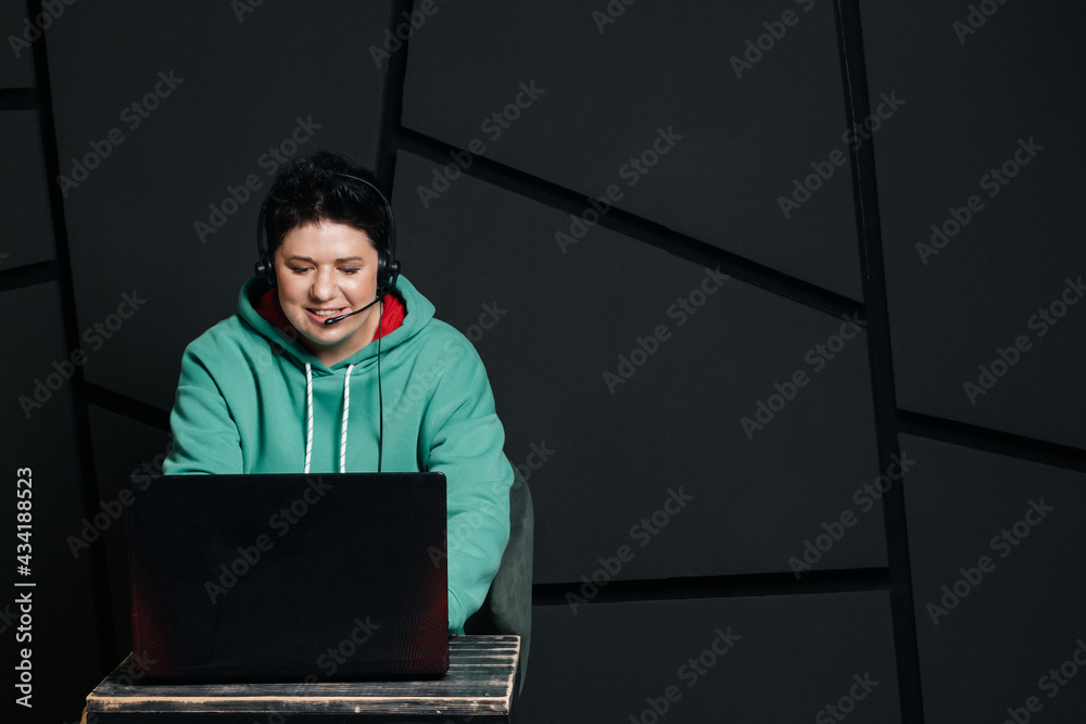 dispatcher, brunette girl with short hair wearing headphones at the computer, working online, on a dark background dispatcher, brunette girl with short hair wearing headphones at the computer, working online, on a dark background