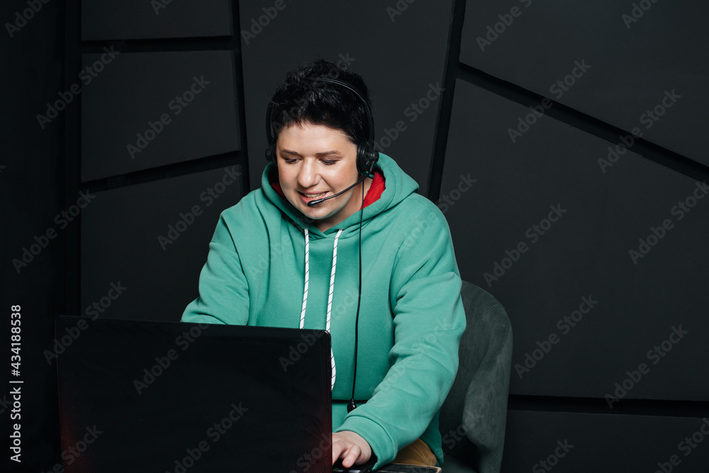 dispatcher, brunette girl with short hair wearing headphones at the computer, working online, on a dark background dispatcher, brunette girl with short hair wearing headphones at the computer, working online, on a dark background