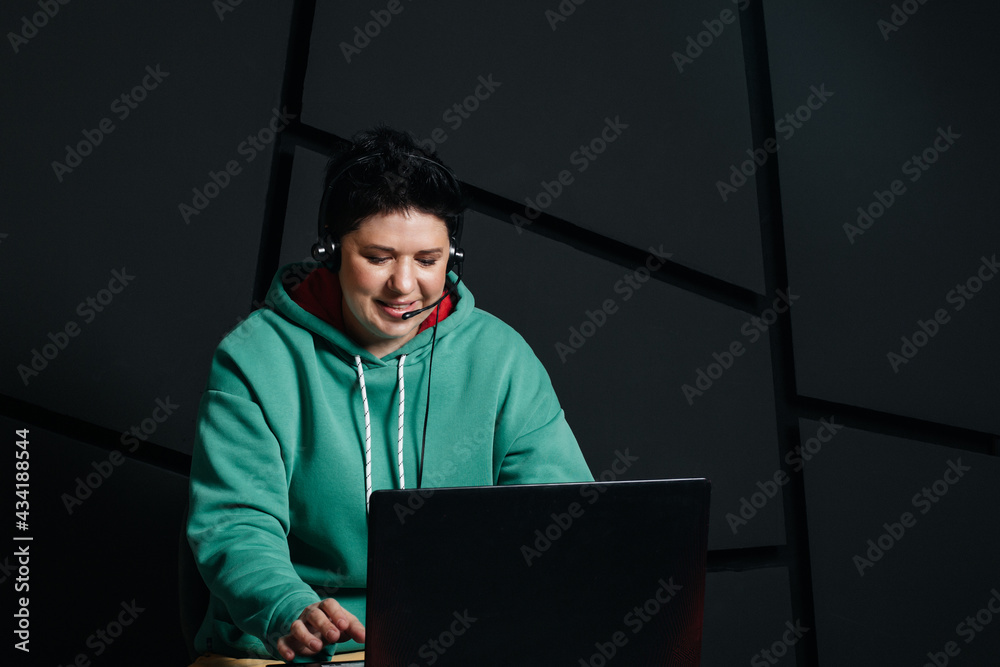 dispatcher, brunette girl with short hair wearing headphones at the computer, working online, on a dark background dispatcher, brunette girl with short hair wearing headphones at the computer, working online, on a dark background
