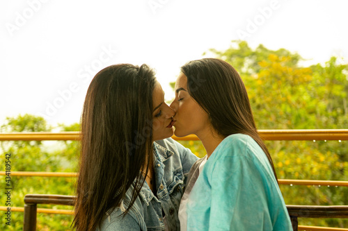 Pareja de jóvenes lesbianas besándose con vista a la naturaleza 