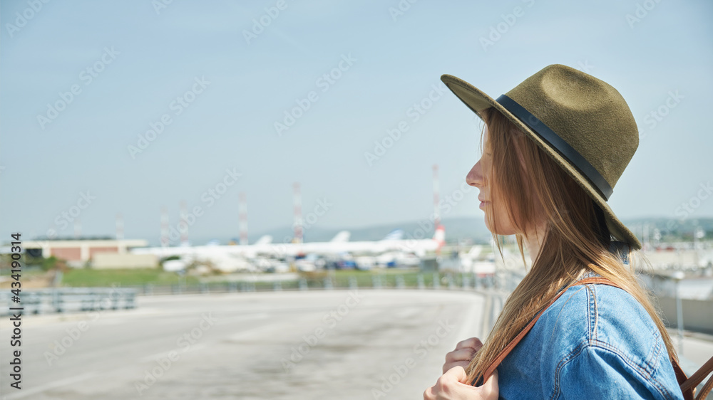Fototapeta premium Girl in hat with backpack standing in the airport. Travel lifestyle.