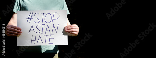 Stop asian hate concept. AAPI inscription, text on paper placard in male hands over black background with copy space for text. photo