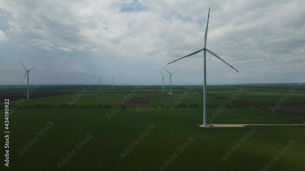 Large wind turbines with blades in the field aerial view blue sky wind park slow motion drone turn. Silhouettes of windmills, summer lenses. alternative energy Large wind turbines with blades in the field aerial view blue sky wind park slow motion drone turn. Silhouettes of windmills, summer lenses. alternative energy