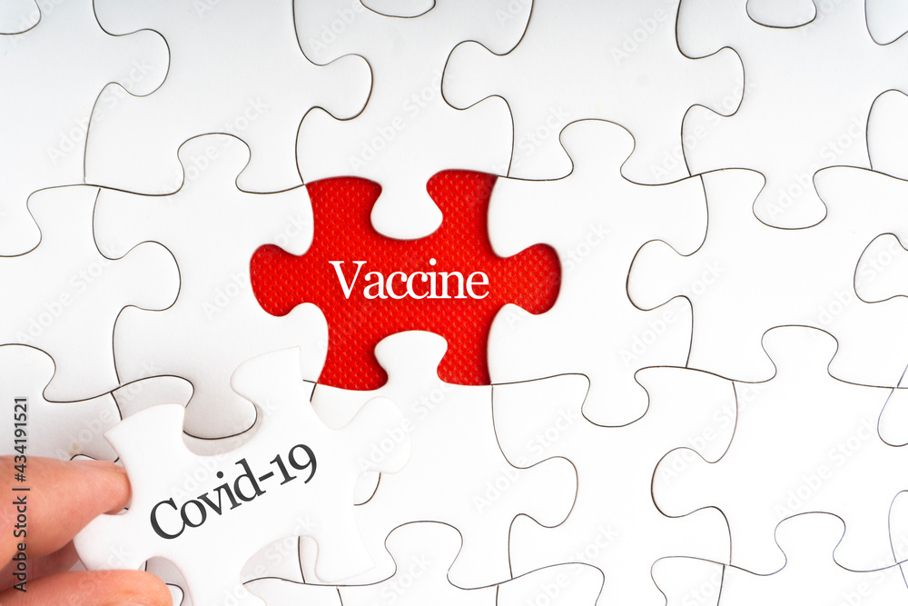 COVID-19 VACCINE text with jigsaw puzzle on red background. Covid-19 and Coronavirus Concept COVID-19 VACCINE text with jigsaw puzzle on red background. Covid-19 and Coronavirus Concept