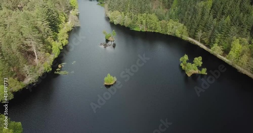 4k aerial footage of Glencoe Lochan showing lochan, surrounding forest, Pap of Glencoe mountain and Loch Leven behind. Cloudy day in springtime.