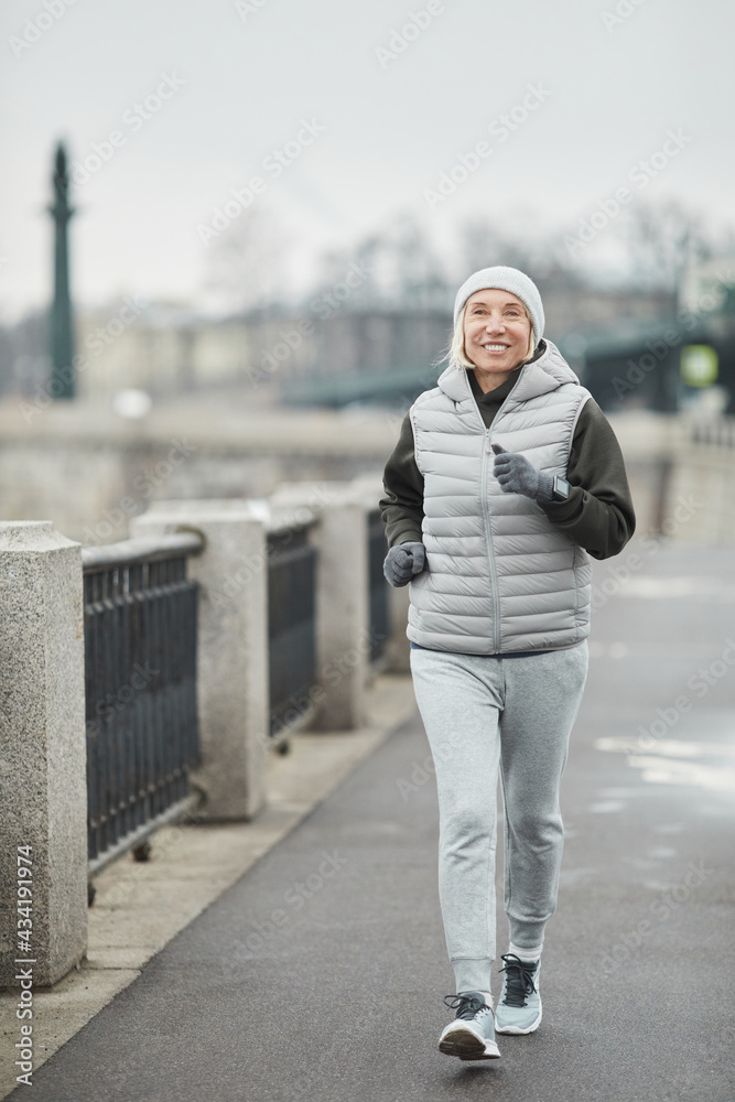 Ταπετσαρία Cheerful beautiful senior woman in hat and gloves using smart watch while brisk