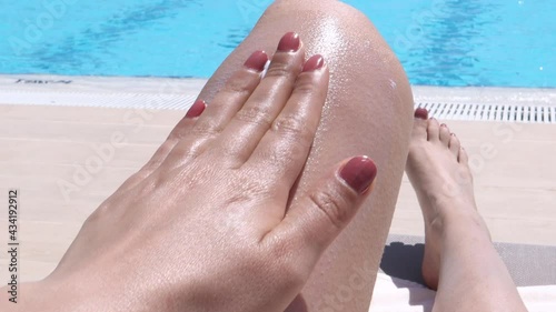 woman applying sunscreen lotion on body - sun skincare  photo