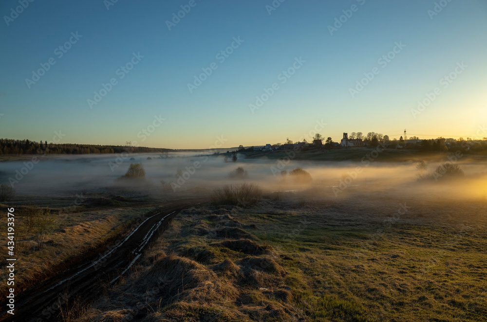 The fog falls on the meadow. Dawn in the village in spring. Morning landscape, Russia