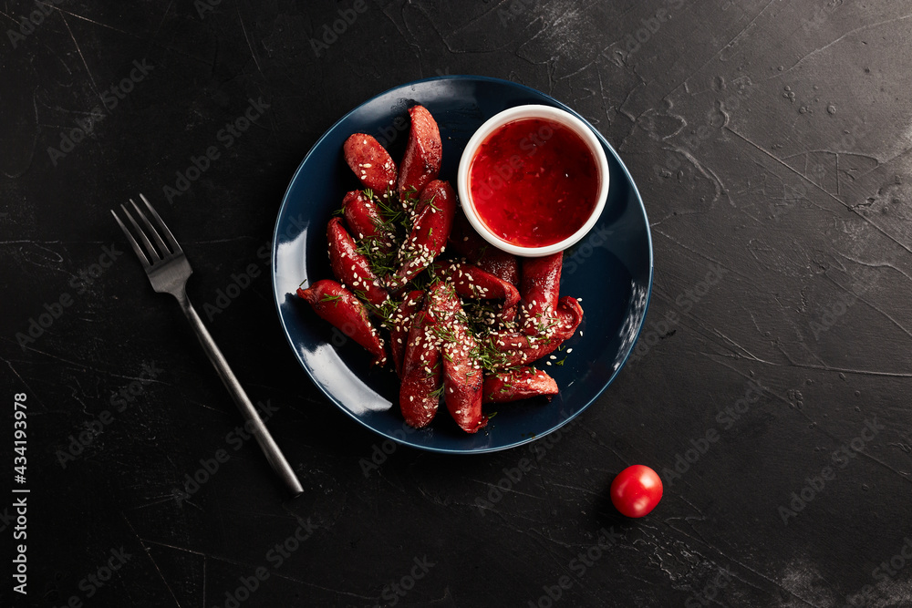 grilled sausages with vegetables on a blue plate on a black background grilled sausages with vegetables on a blue plate on a black background