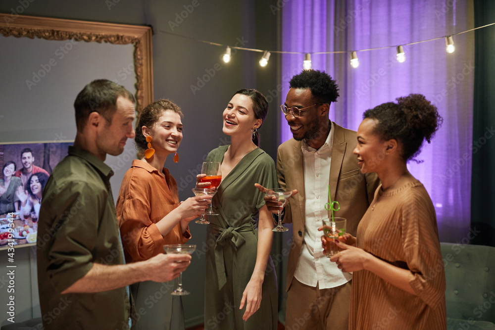 Waist up portrait of diverse group of friends laughing and chatting while enjoying party at home - obrazy, fototapety, plakaty 