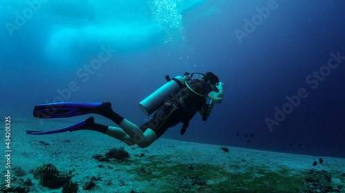 Wallpaper Mural Young diver adjusts goggles just at beginning of diving session. Murky water, sandy bottom, boat silhouette at the water surface, anchor chain at left background Torontodigital.ca