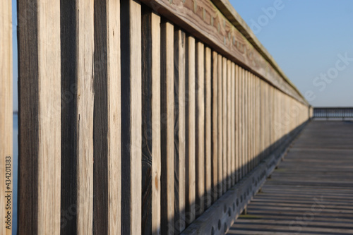 Uniform wooden railing on a coastal pier repeating into the distance