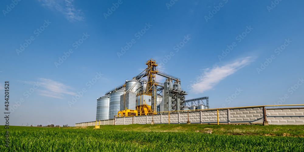 Obraz premium Modern Granary elevator. Silver silos on agro-processing and manufacturing plant for processing drying cleaning and storage of agricultural products, flour, cereals and grain. seed cleaning line