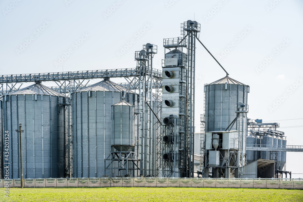 Obraz premium Modern Granary elevator. Silver silos on agro-processing and manufacturing plant for processing drying cleaning and storage of agricultural products, flour, cereals and grain. seed cleaning line