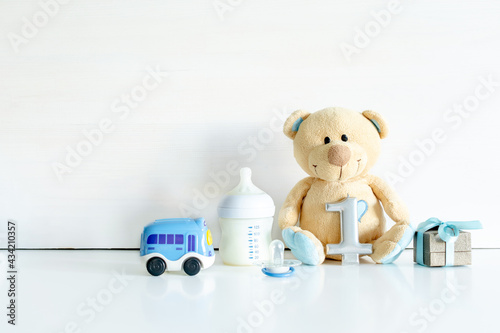 Teddy bear toy, gift box, digit one on white table with copy space. Baby shower, accessories, decorations, stuff, present for boy girl child first year happy birthday, first newborn party background