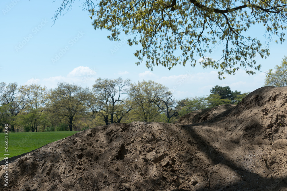 piles of dirt or sandy soil from a nearby excavation being stored near a play field surrounded by trees piles of dirt or sandy soil from a nearby excavation being stored near a play field surrounded by trees