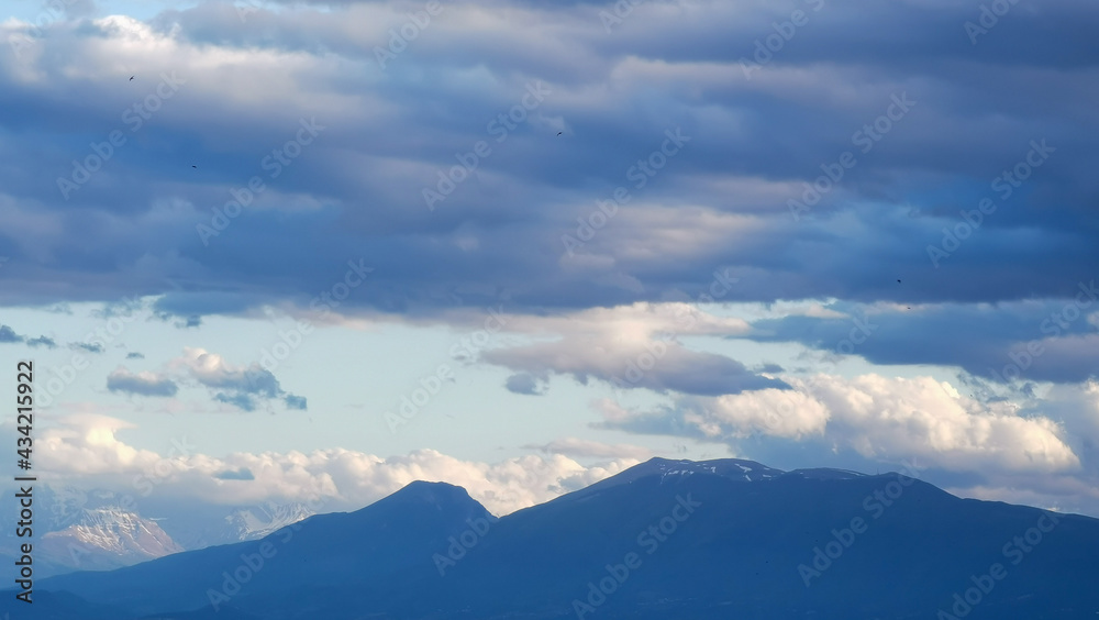 Grandi nuvole sopra le montagne dell’Appennino all’imbrunire in un cielo azzurro primaverile