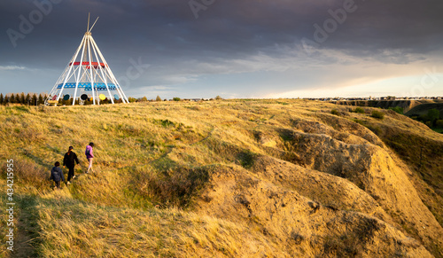 Medicine Hat Alberta Canada, May 13 2021: A family walks outdoors along a hiking trail in Seven Persons Coulee by the Sammis Tepee at sunset. photo