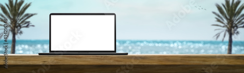 laptop on a table on a sunny day in the summer with beach in the background