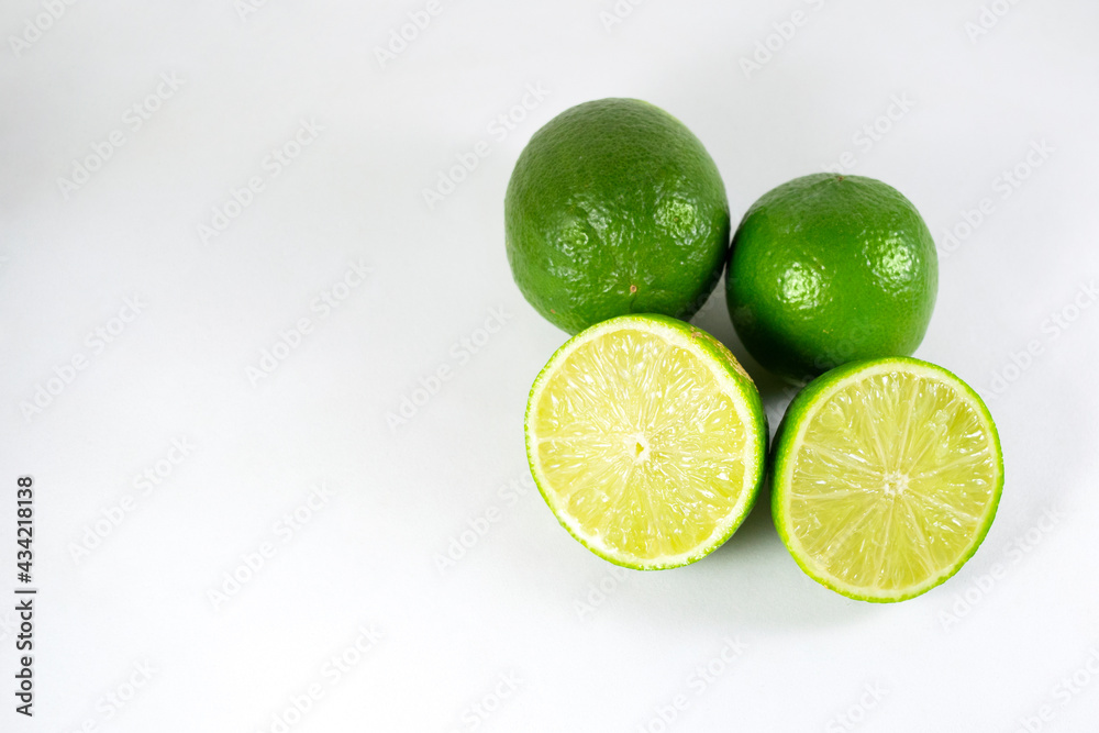 Isolated Tahiti lemons and one sliced fruit on a white background and a blank space on the left. Isolated Tahiti lemons and one sliced fruit on a white background and a blank space on the left.