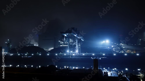 Crane of Coal fired power station on the edge of river works in the blue industrial light of the night photo