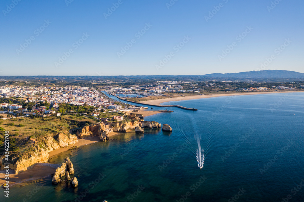Fototapeta premium Camilo Beach at sunrise. Lagos, Algarve - Portugal. Portuguese southern golden coast cliffs. Sunny day aerial view.