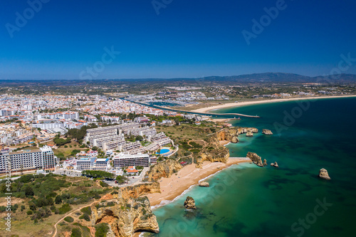 Dona Ana Beach in Lagos, Algarve - Portugal. Portuguese southern golden coast cliffs. Aerial view with city in the background.