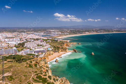 Dona Ana Beach in Lagos, Algarve - Portugal. Portuguese southern golden coast cliffs. Aerial view with city in the background