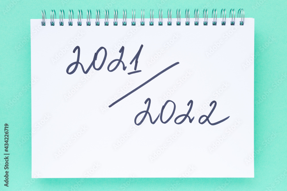 New academic year 2021-2022. Back to school concept. Handwriting inscription in white notepad, on vivid red background. Flat lay, top view. New academic year 2021-2022. Back to school concept. Handwriting inscription in white notepad, on vivid red background. Flat lay, top view.