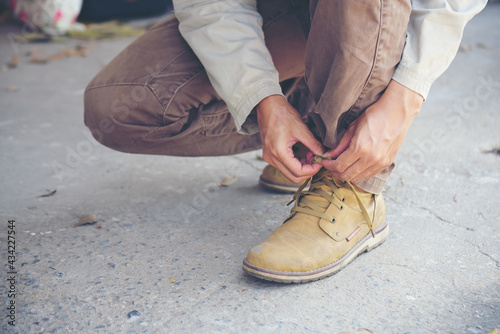 Man kneel down and tie shoes industry boots for worker. Close up shot of man hands tied shoestring for his construction brown boots. Close up man hands tie up shoes for footwear concept.