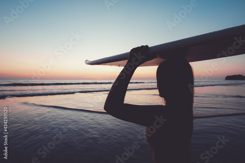 Photography Silhouette of beautiful sexy surfer female with surfboard on the sandy beach at sunset