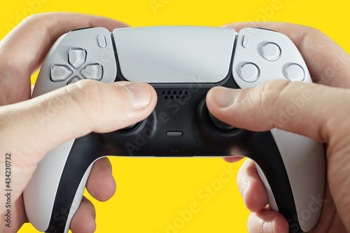 hand holding next generation joystick on yellow background - game controller.