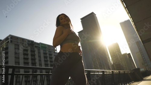 Female hip hop dancer confident dancing outdoor by the river rail toned body face expressions cinematic golden hour sunset scenery city envronment photo