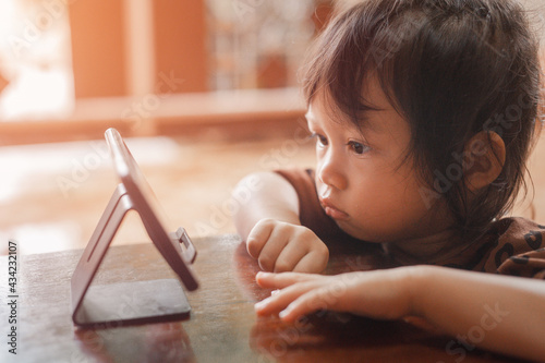 Little cute beautiful girl, Asian people sit and watch their smartphone very focused and intently. The idea of children being too addicted to smartphones in watching cartoons and playing games