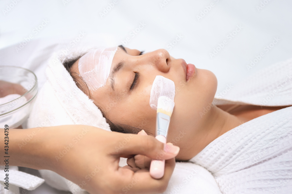 Asian young women lying relax using mask brush, moisturize their skin, making skin hydrated, helps with homemade apply face mask. Leisure activity at home.