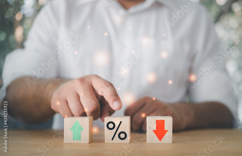 Business man chooses a wood cube block percent symbol icon with plus and minus. Concept of financia