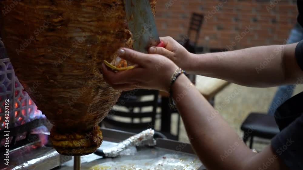 trompo de pastor, mexican food concept. man cutting the meat from the trompo to make tacos de pastor