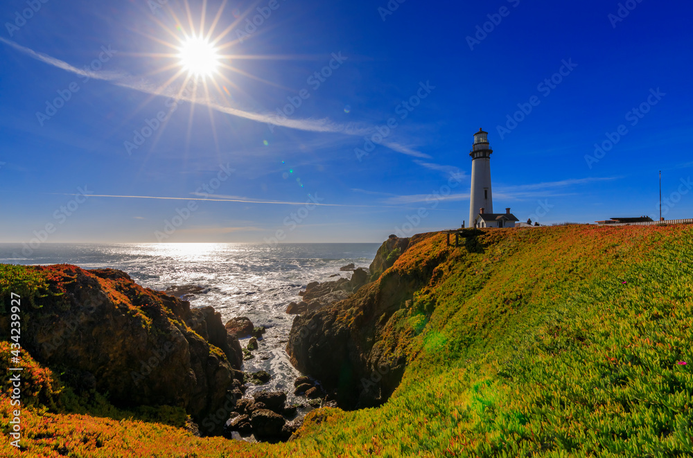 Artistic sun flare and waves crashing on the shore by Pigeon Point Lighthouse on Northern California Pacific Ocean coastline near Pescadero