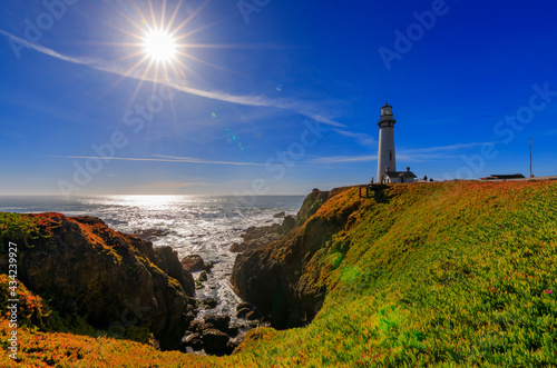 Artistic sun flare and waves crashing on the shore by Pigeon Point Lighthouse on Northern California Pacific Ocean coastline near Pescadero