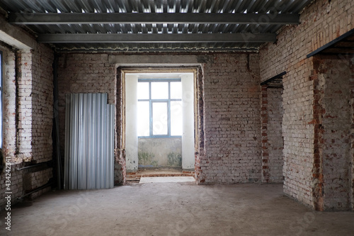 Abandoned building with brick walls daytime Interior. Interior of shabby room with weathered brick walls in desolated building at daytime
