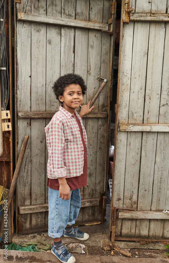 African little boy opening the wooden door while spending time on fresh air in the countryside African little boy opening the wooden door while spending time on fresh air in the countryside