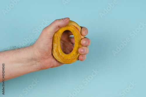 The hand is clutching a yellow rubber band on a blue background.