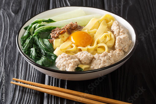 Singapore style homemade noodle soup with fried anchovies, meatballs, egg and bok choy close-up in a bowl on the table. horizontal photo