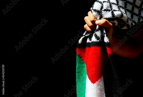 Schilderij op canvas Asian child hand with Palestine scarf, on dark background
