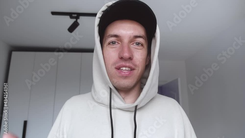 POV of handsome young man making video call from home waving hand talking enjoying communication. Young smiling male blogger recording selfie video blog indoors.