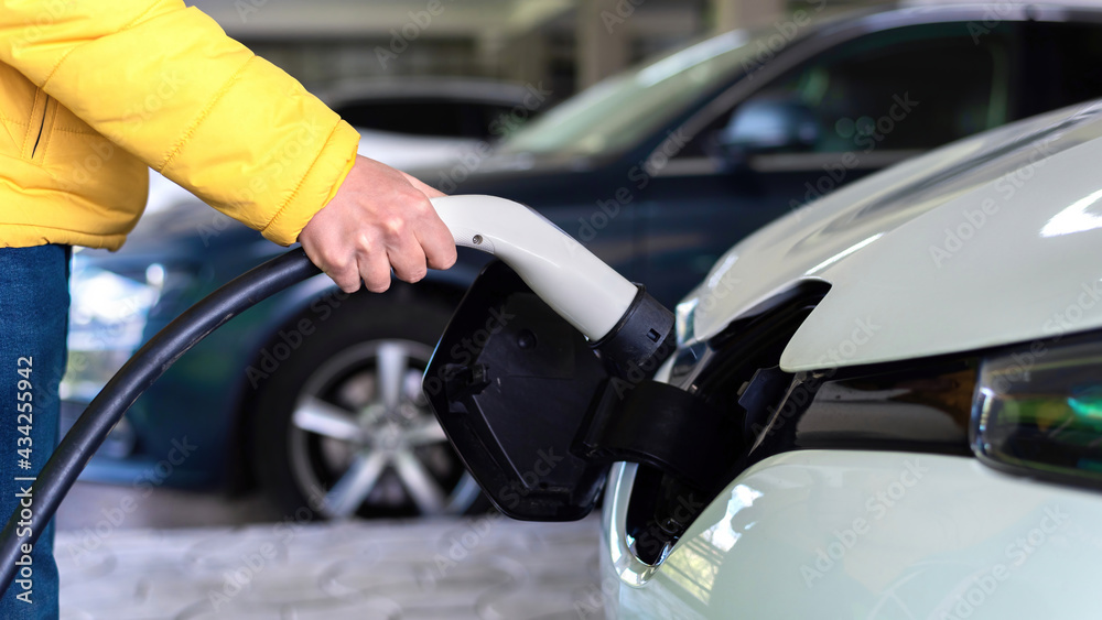 Plugging in charger into an electric car Plugging in charger into an electric car